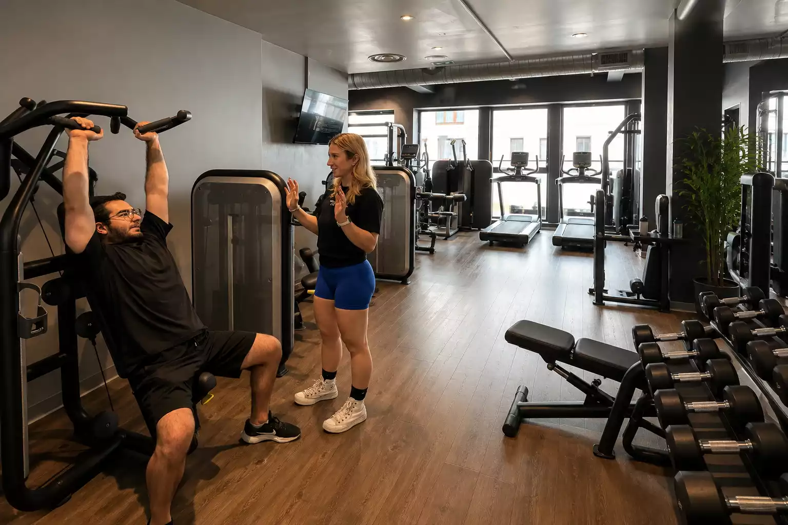 Deux personnes en salle de sport Keepcool utilisant machine à latissimus pour musculation guidée