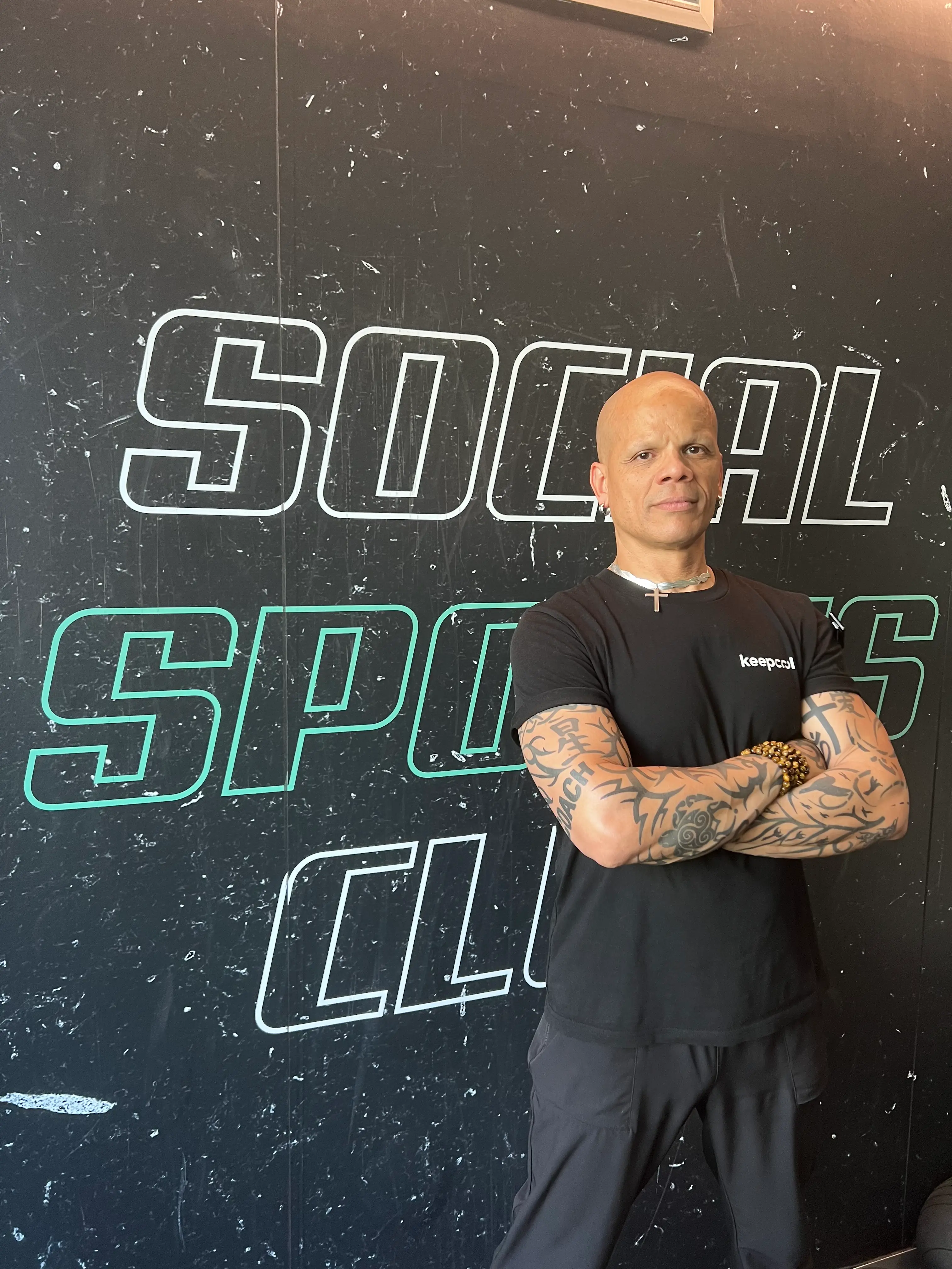 Franck, coach sportif Keepcool, pose devant enseigne Social Sports Club salle de sport moderne.