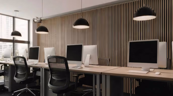 A sleek looking corporate office with computer monitors, chairs and lighting and textured wall.