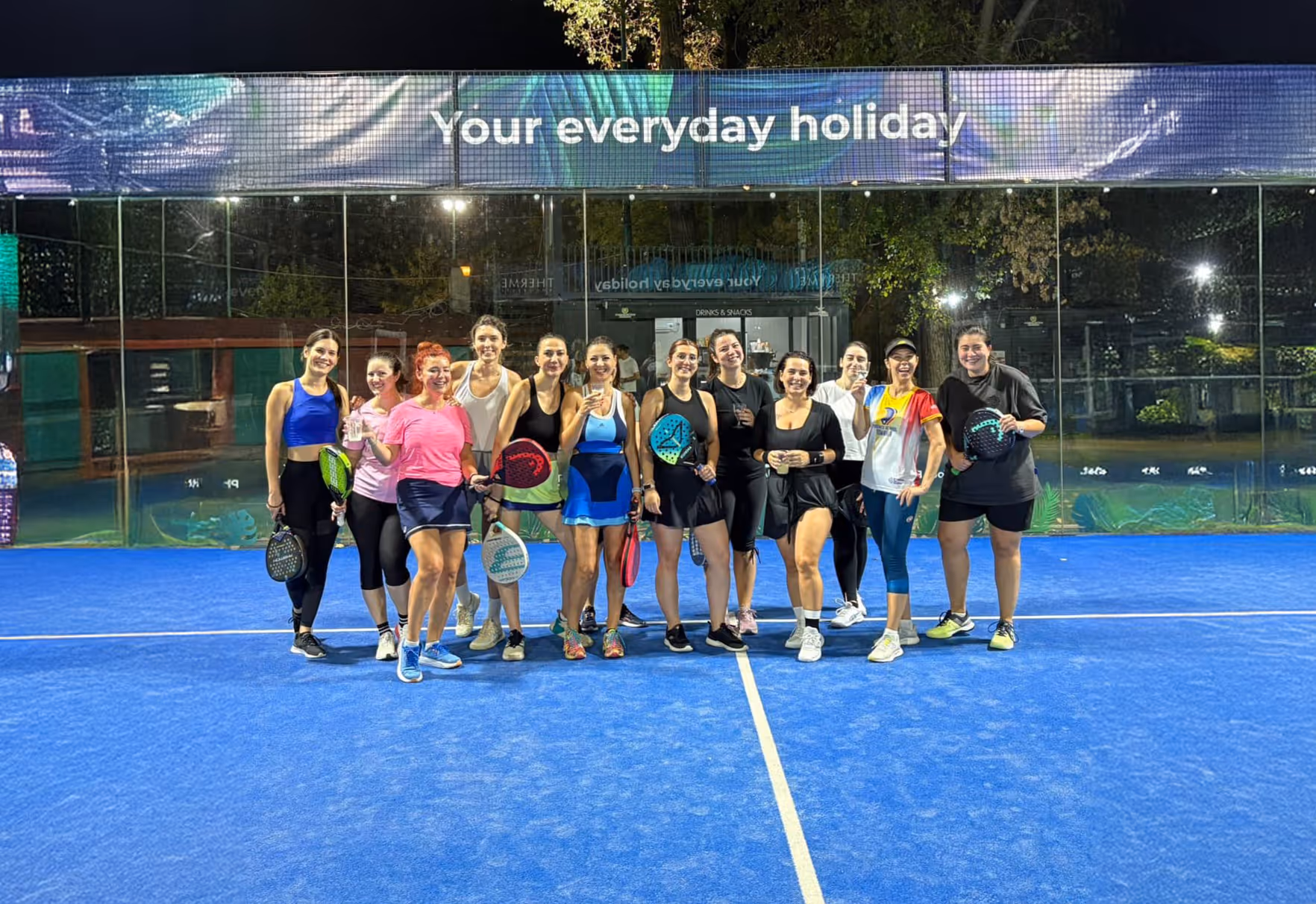 Grup de jucătoare zâmbitoare cu rachetele, seara, pe terenul PADELMANIA Herăstrău