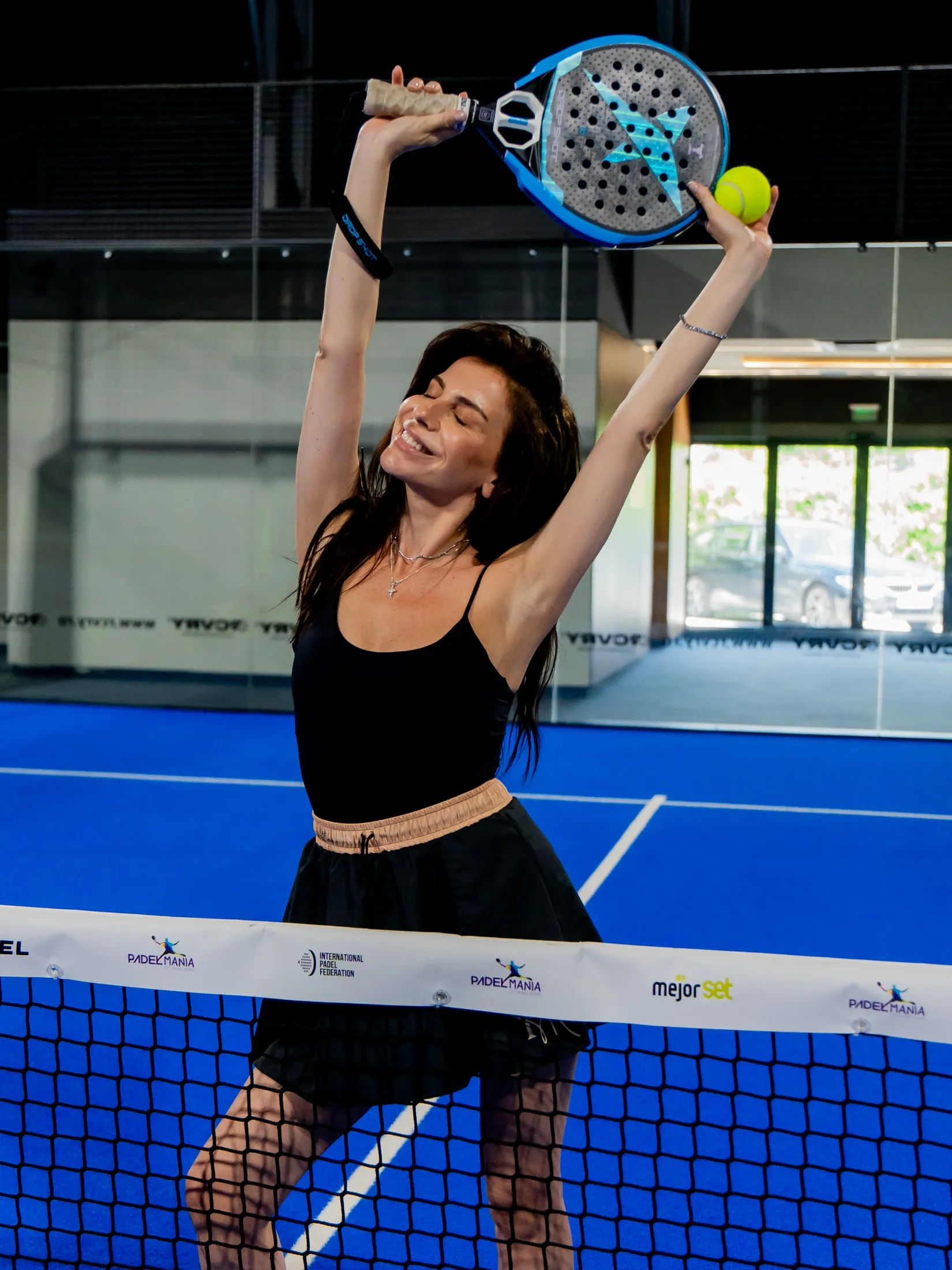 Jucătoare care se bucură la fileu, cu racheta ridicată, pe un teren PADELMANIA