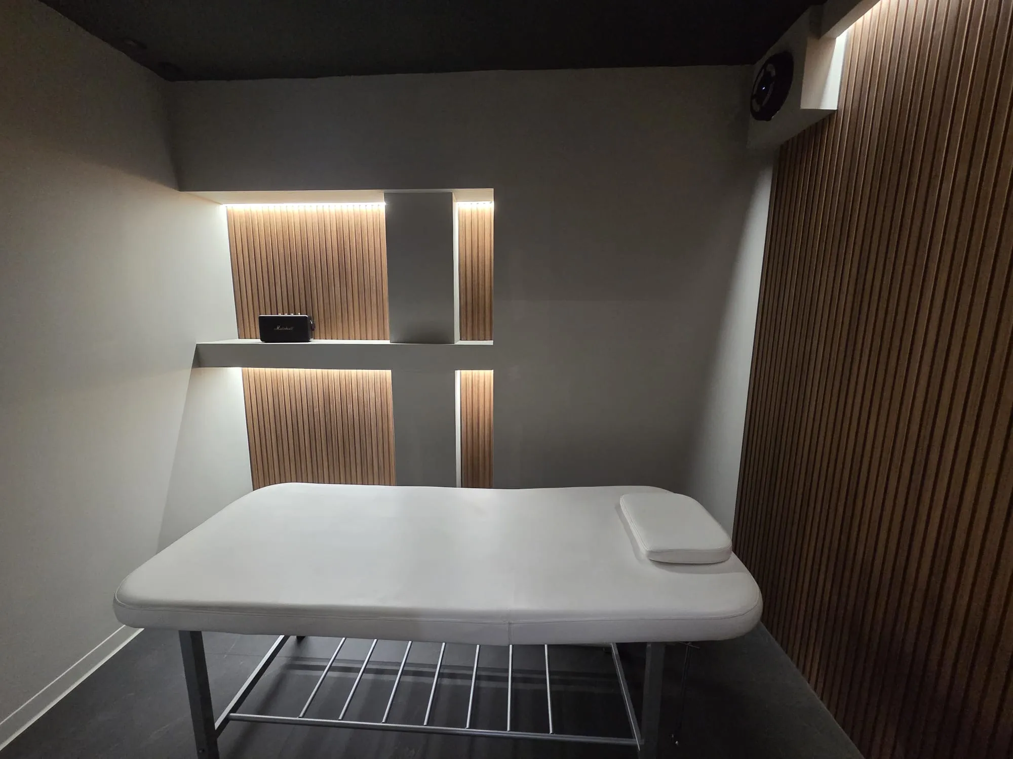 Sala de masaj de la PADELMANIA Tunari, cu masă de masaj și panouri din lemn