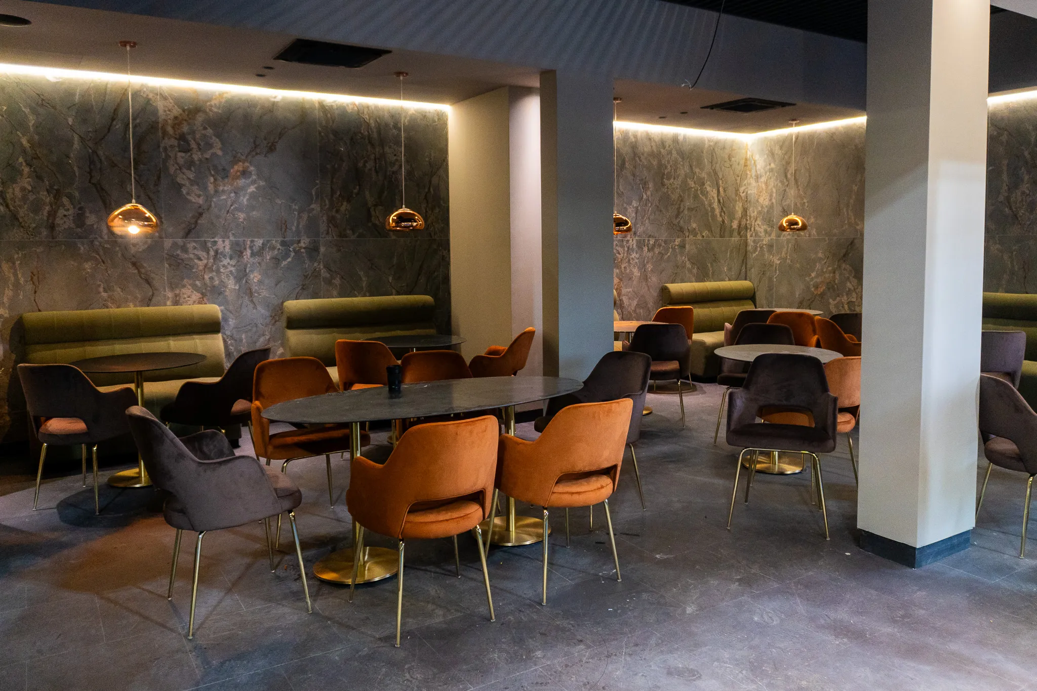 Sala MANA Restaurant, cu fotolii din catifea, lămpi suspendate și perete de marmură