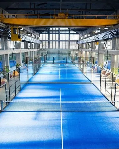 Terenuri de padel albastre într-o hală industrială cu pod rulant, la Padel Resort din Como, Italia