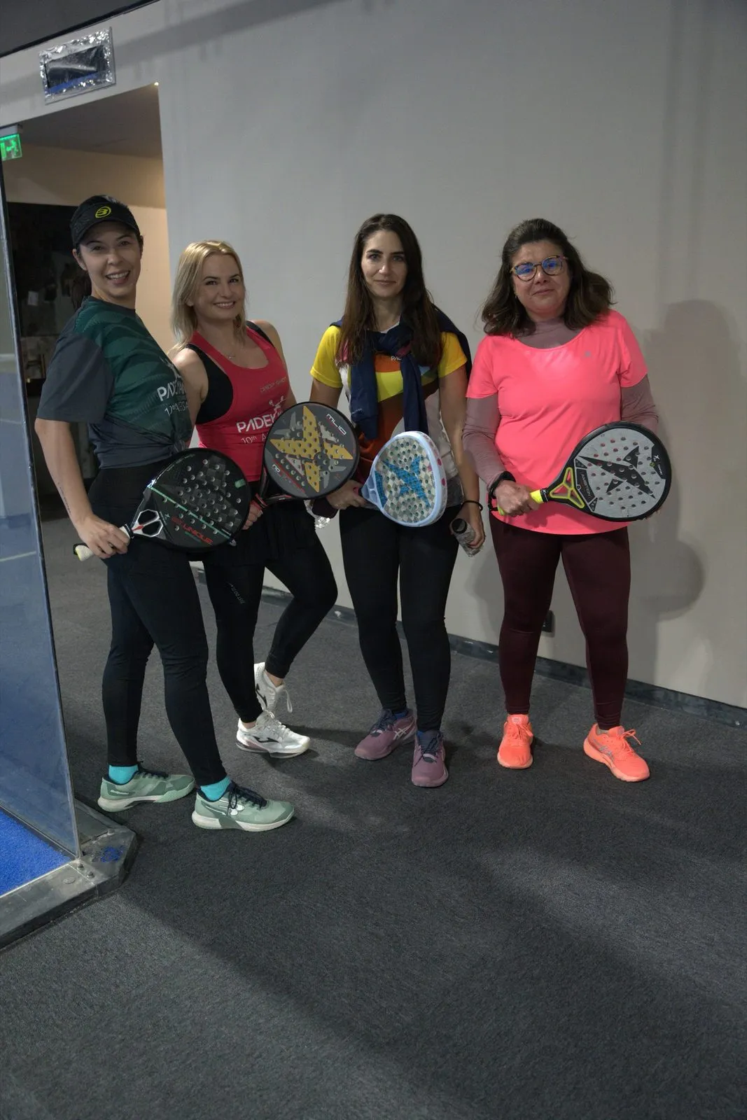 Patru prietene zâmbitoare cu rachetele, înainte de joc, la PADELMANIA Tunari