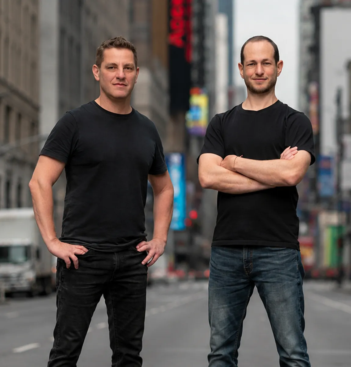 Shuttlebase Founders in black t-shirts stand confidently on a city street with blurred buildings behind them.