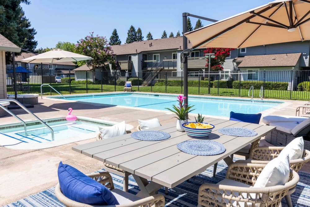Picnic table with umbrella near swimming pool and hot tub with lounge chairs