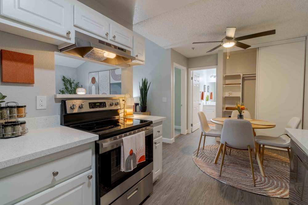 Kitchen with white cabinets, stainless steel appliances and view into Dining area with table and chairs
