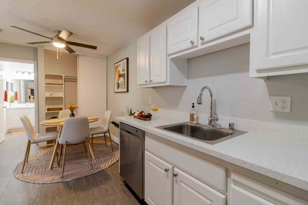 Kitchen with white cabinets, stainless steel appliances and view into Dining area with table and chairs