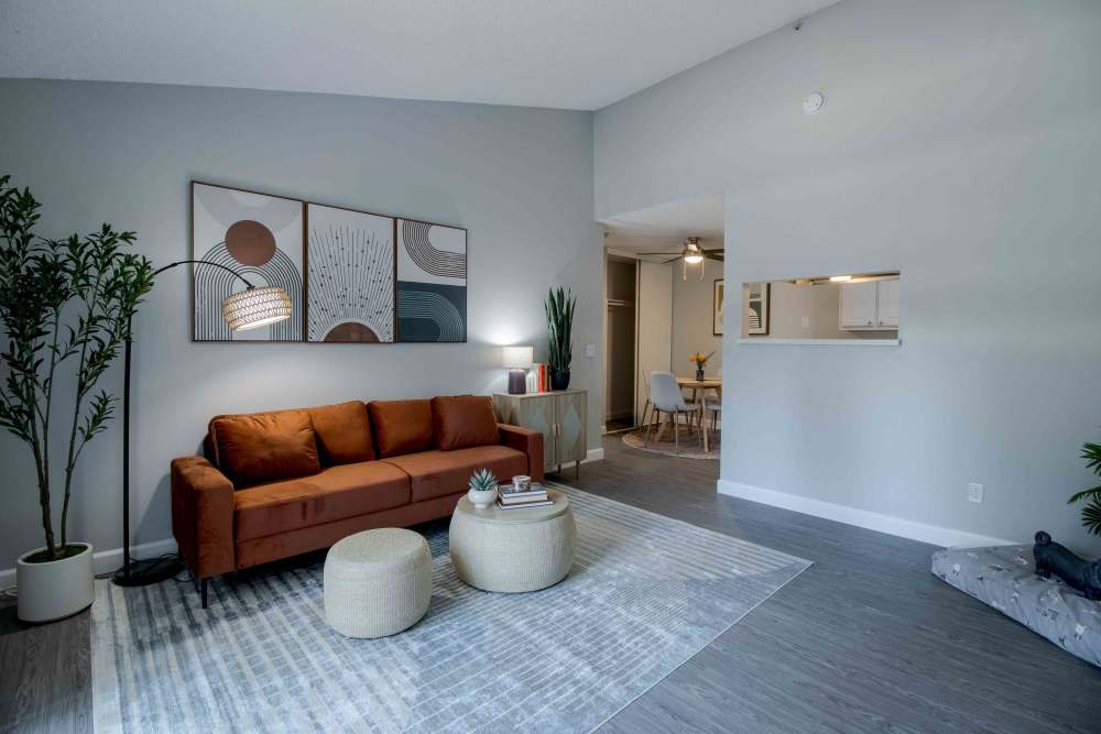 Living area with sofa, rug, plant, and modern wall art and view into dining room 