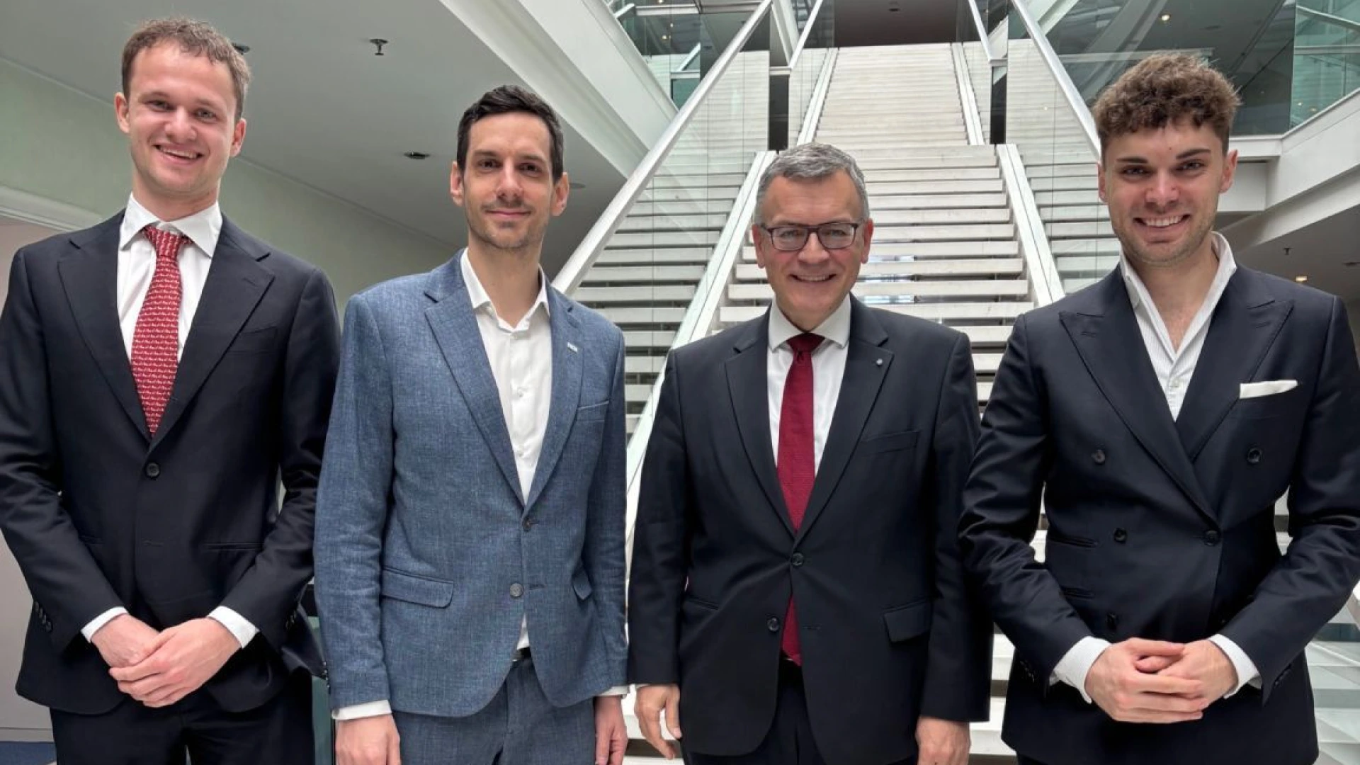 4 people in formal clothing standing side by side.