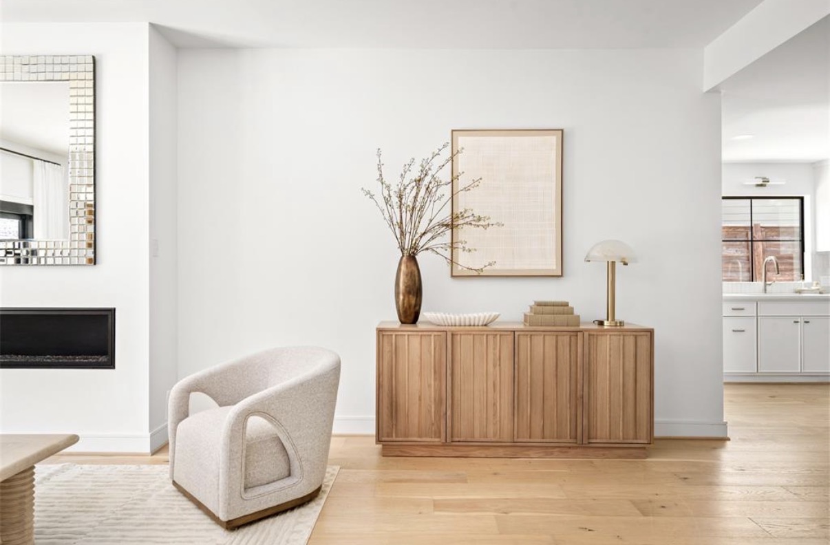 Modern bathroom with curved terracotta-colored walls, a concrete vanity with vessel sink, decorative vases, arched mirror, and a freestanding bathtub in the background.