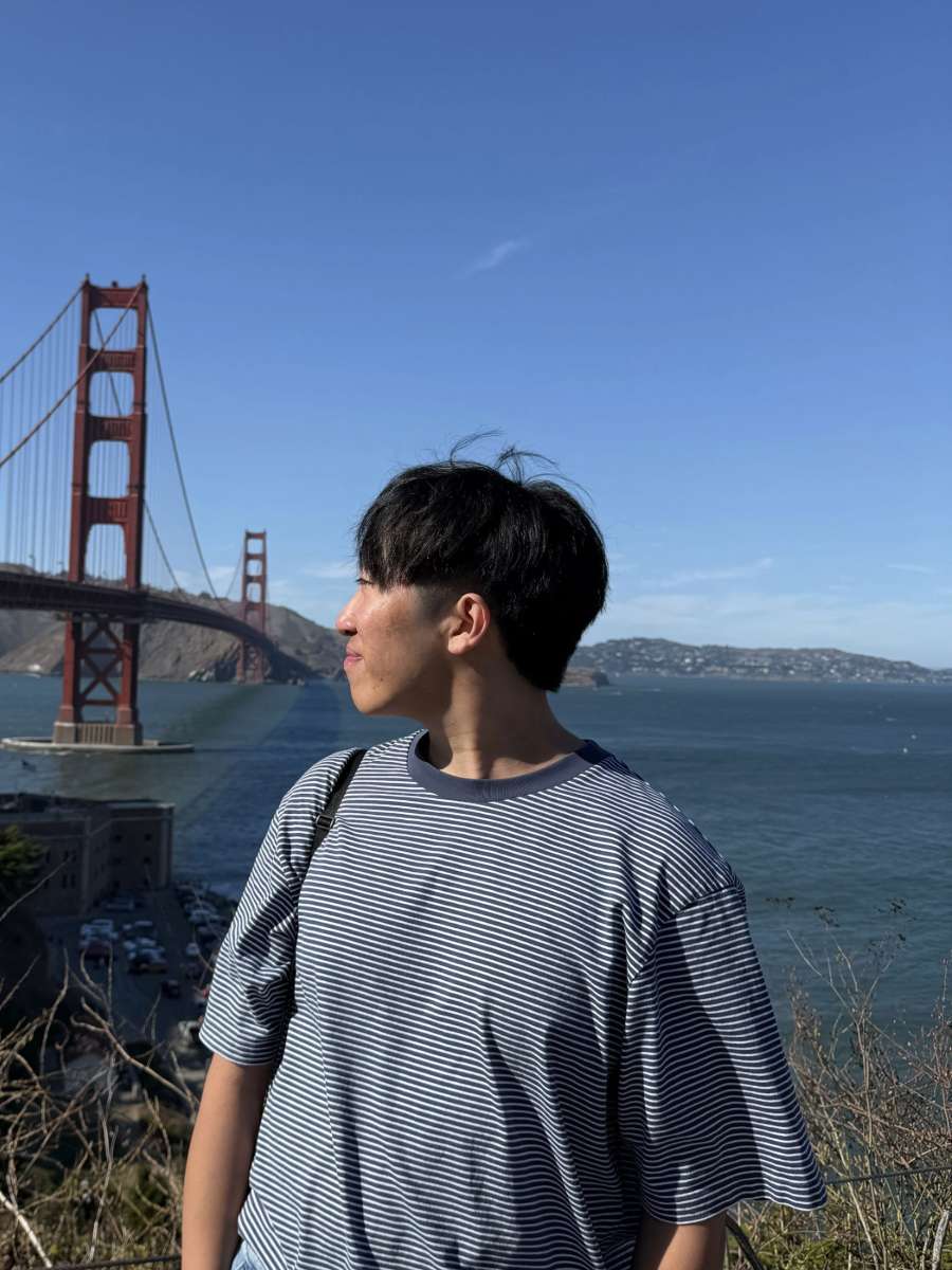 A man looking at the Golden Gate Bridge with the bay behind him.