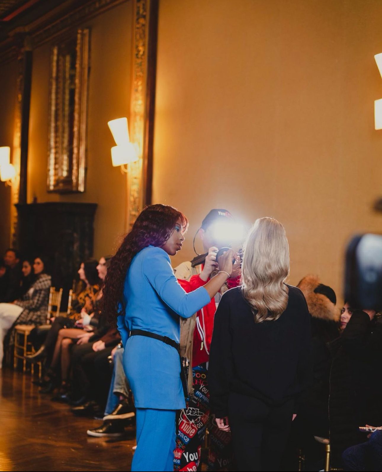 MHG founder Precious Osuji doing makeup on a model during a runway show