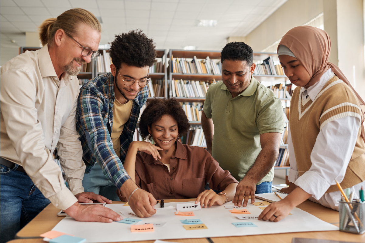 Diverse group smiling and collaborating on a project with sticky notes in a library setting.