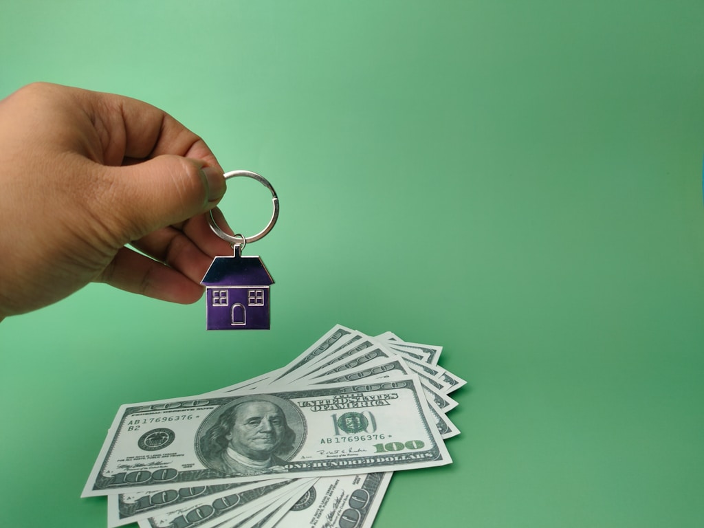 Hand holding house keychain and banknotes