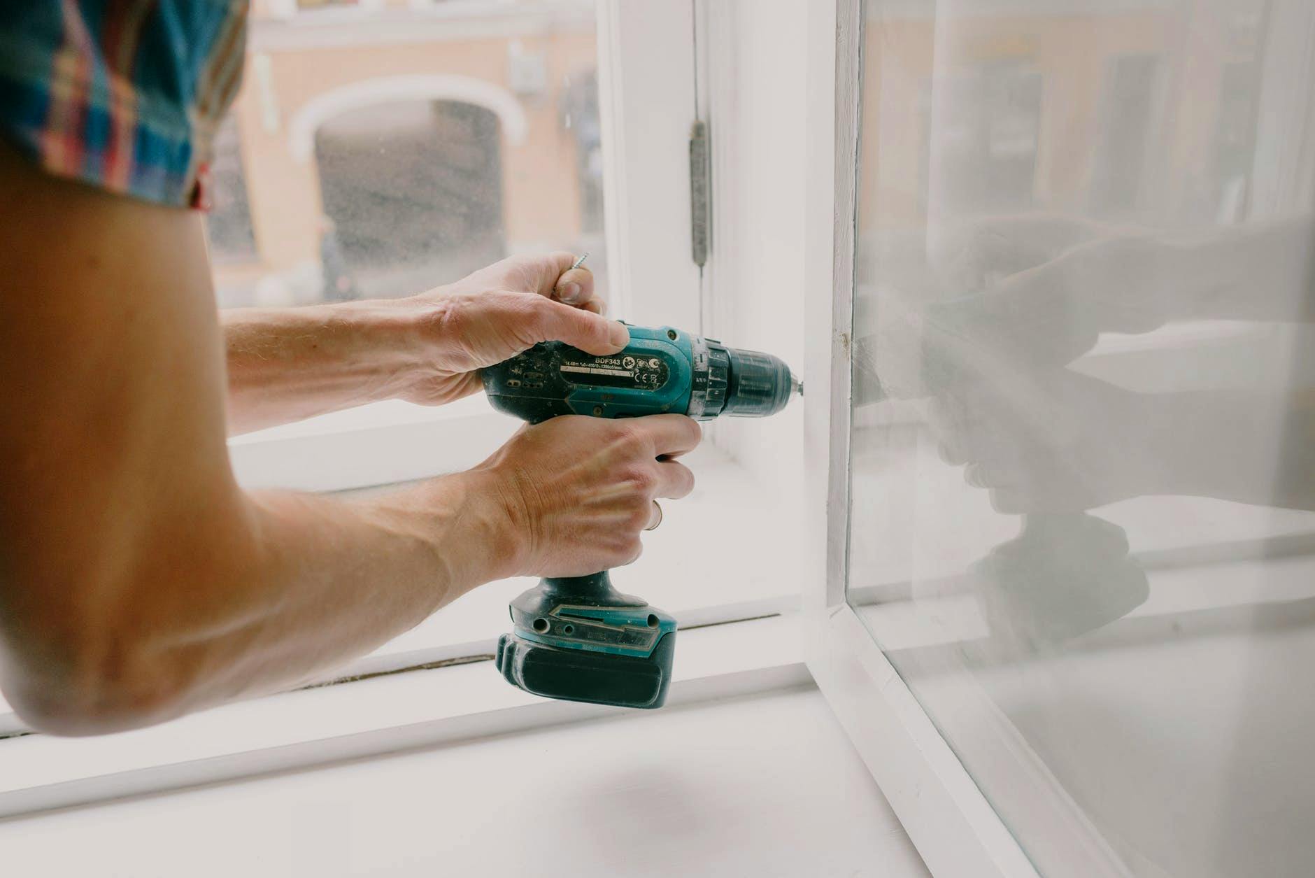workman screwing window frame during housework