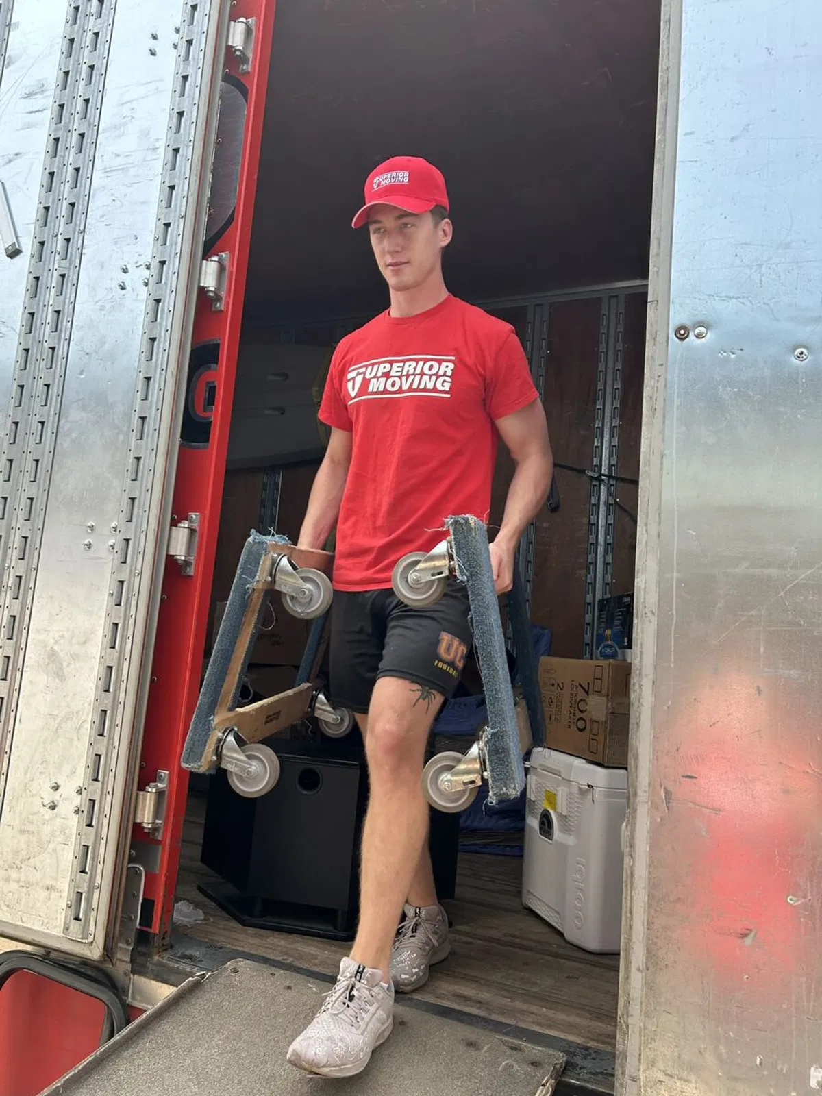 A Superior Moving and Storage employee steps down a ramp from a moving truck carrying professional dollies