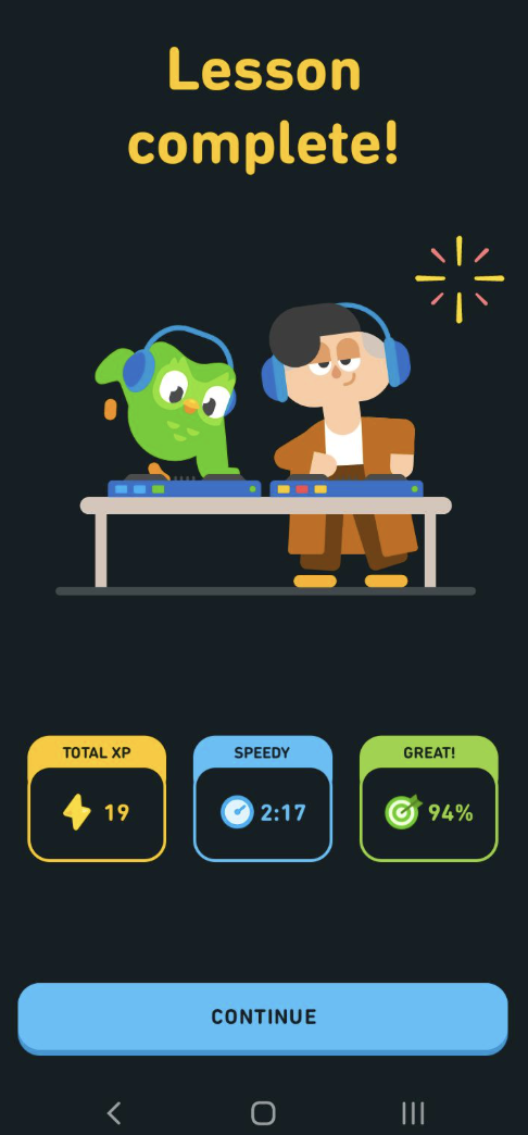 Lesson complete screen with Duolingo owl and person wearing headphones, showing scores and continue button.