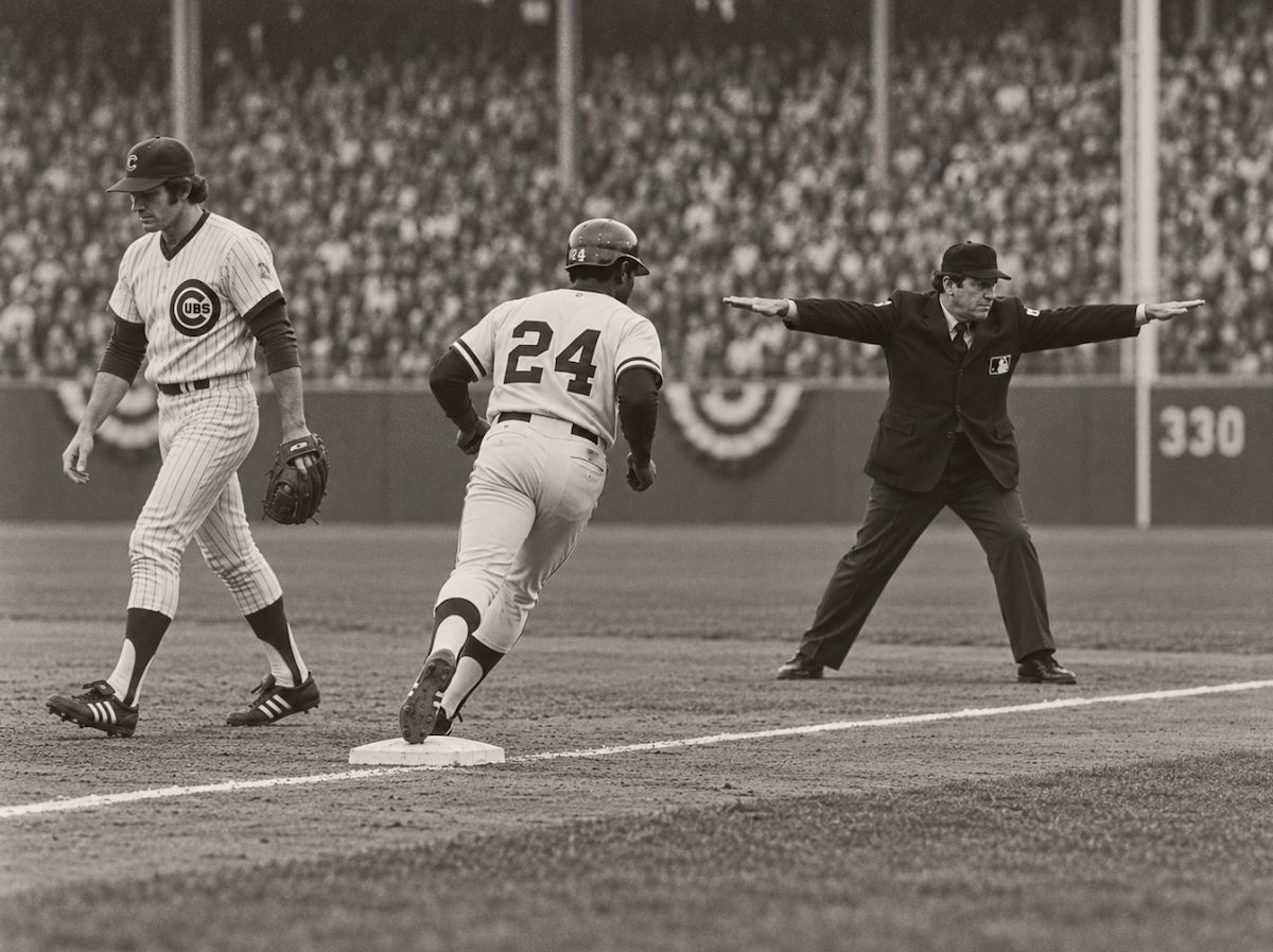 An umpire signals safe as the runner reaches first without a hit.