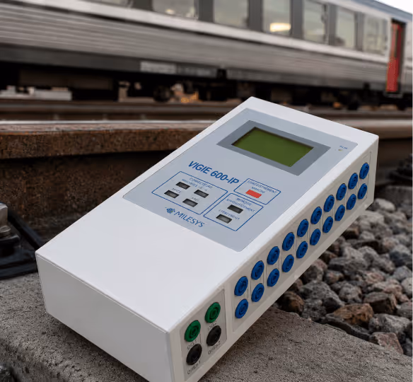 Appareil VIGIE 600-IP de Milesys posé sur une voie ferrée avec un train en arrière-plan.