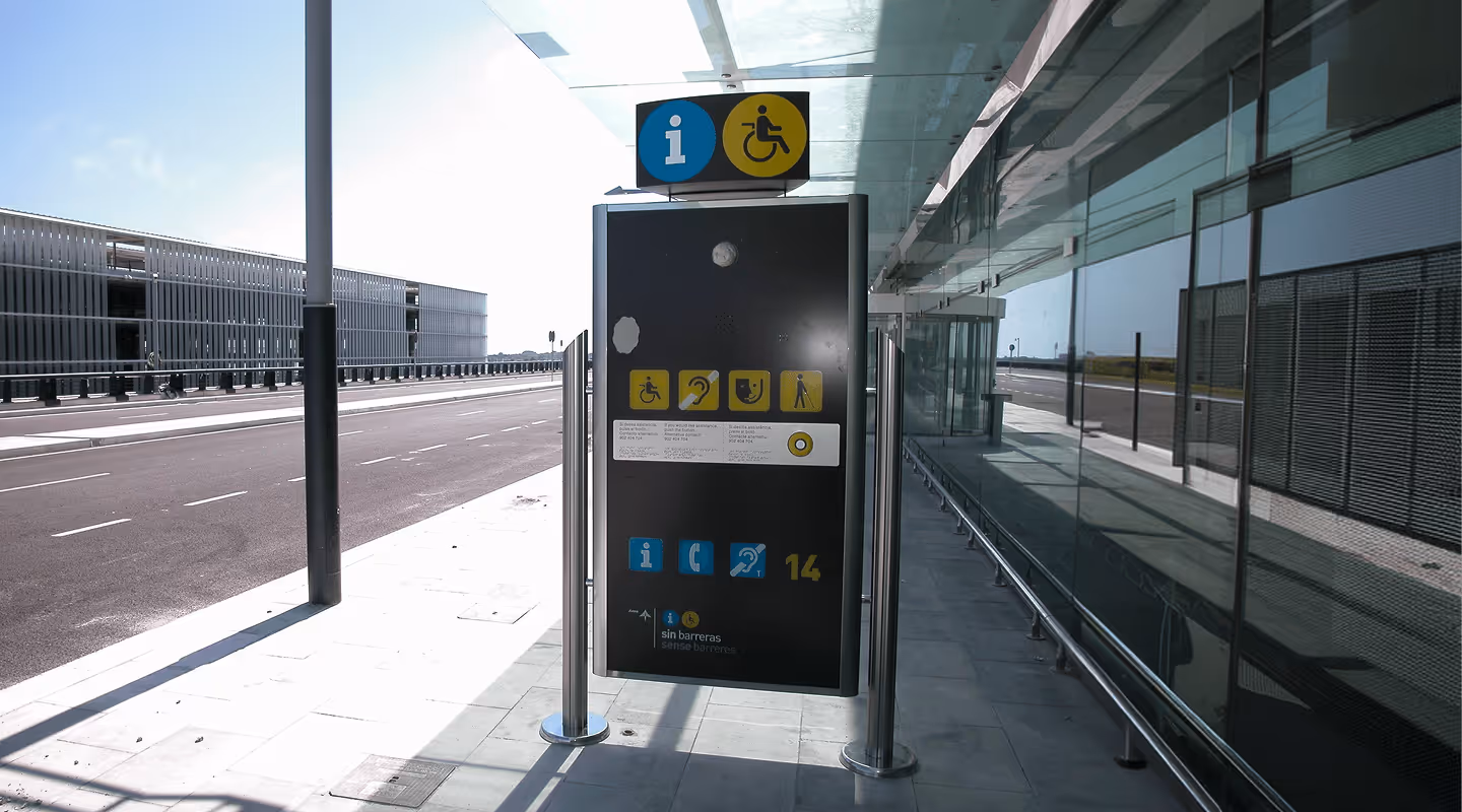 Signalétique d’information et d’accessibilité pour personnes handicapées à l’extérieur, près d’un bâtiment moderne.