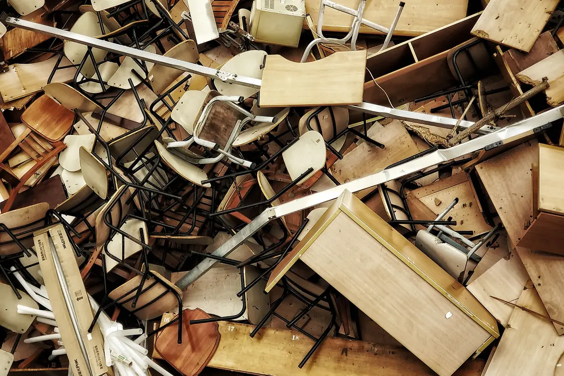 Pile of surplus office desks, chairs and shelving cleared out during an office move and furniture liquidation