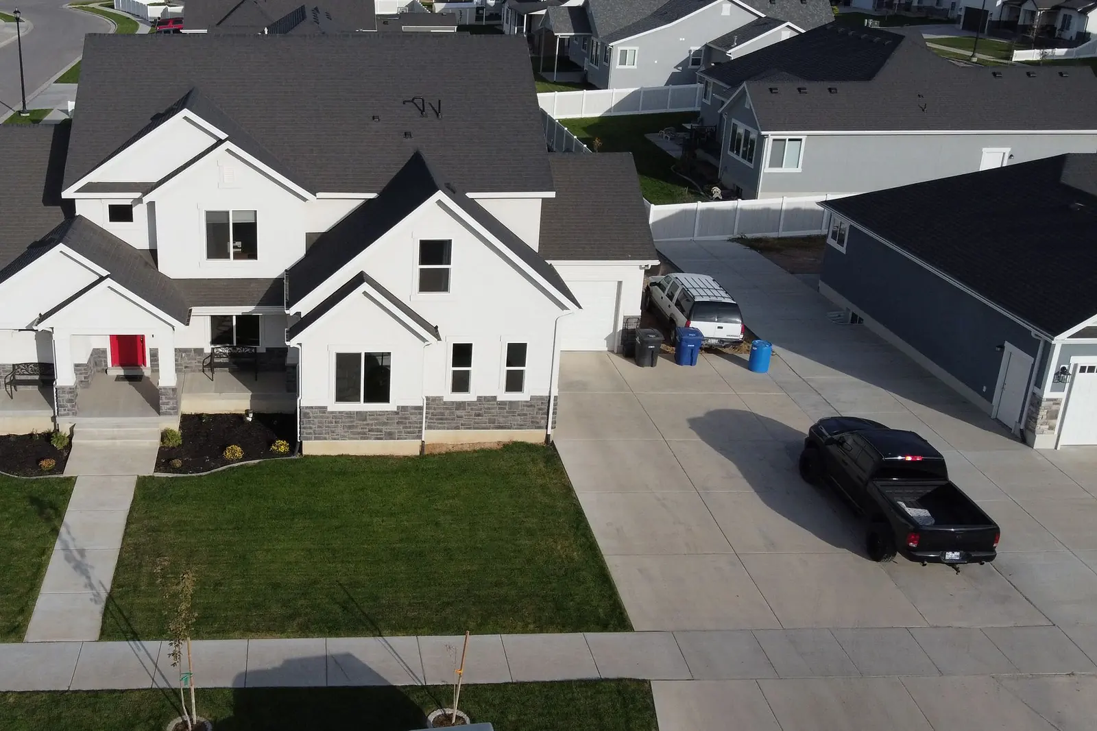 Aerial view of a wide concrete driveway at a two-story home, the kind of surface a roll-off dumpster is set down on