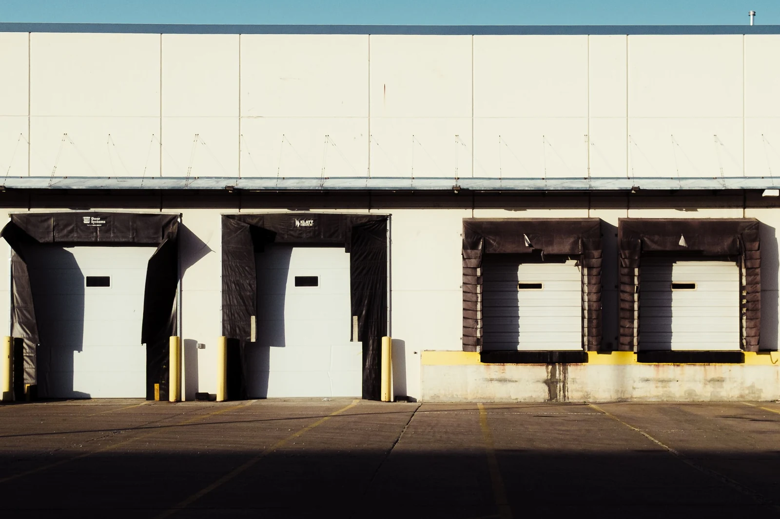 Loading dock bays at a commercial warehouse where a permanently placed waste container is serviced on a schedule