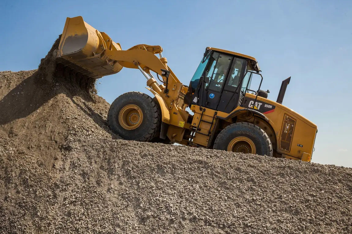Wheel loader on a crushed rock stockpile tipping aggregate for material delivery to a job site
