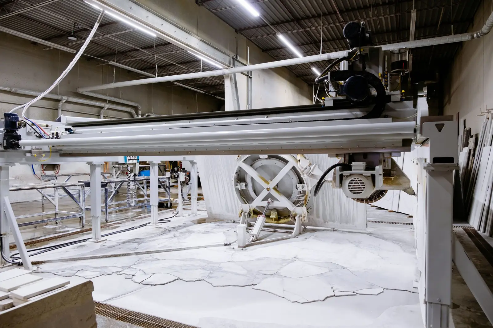 CNC bridge saw in a countertop fabrication shop with stone slurry on the floor and racked stone remnants