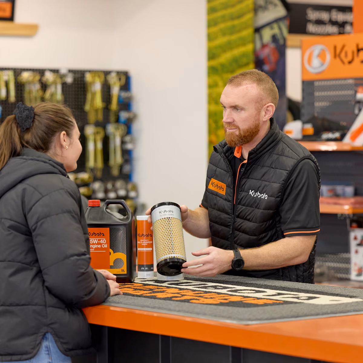 Parts team member handing a Kubota oil filter to a customer across the parts counter.
