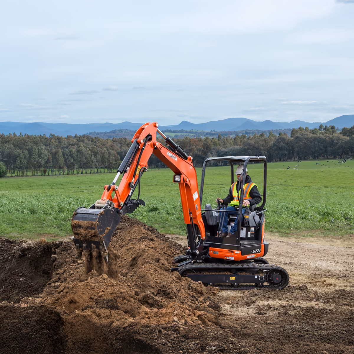 Kubota mini excavator digging in a farm paddock