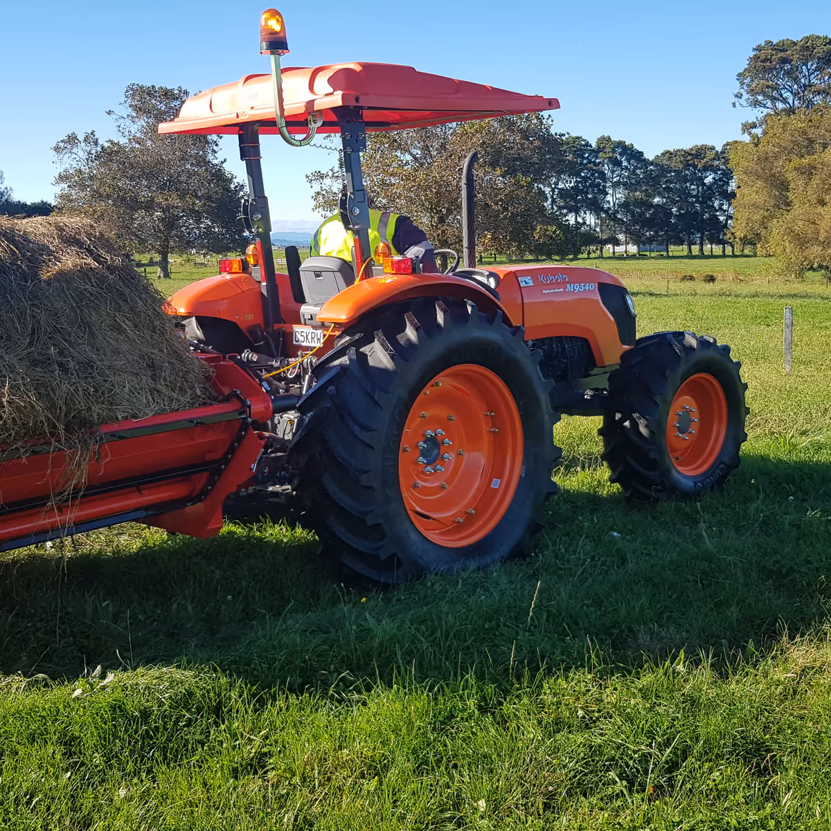 Kubota tractor beside a round hay bale in a paddock
