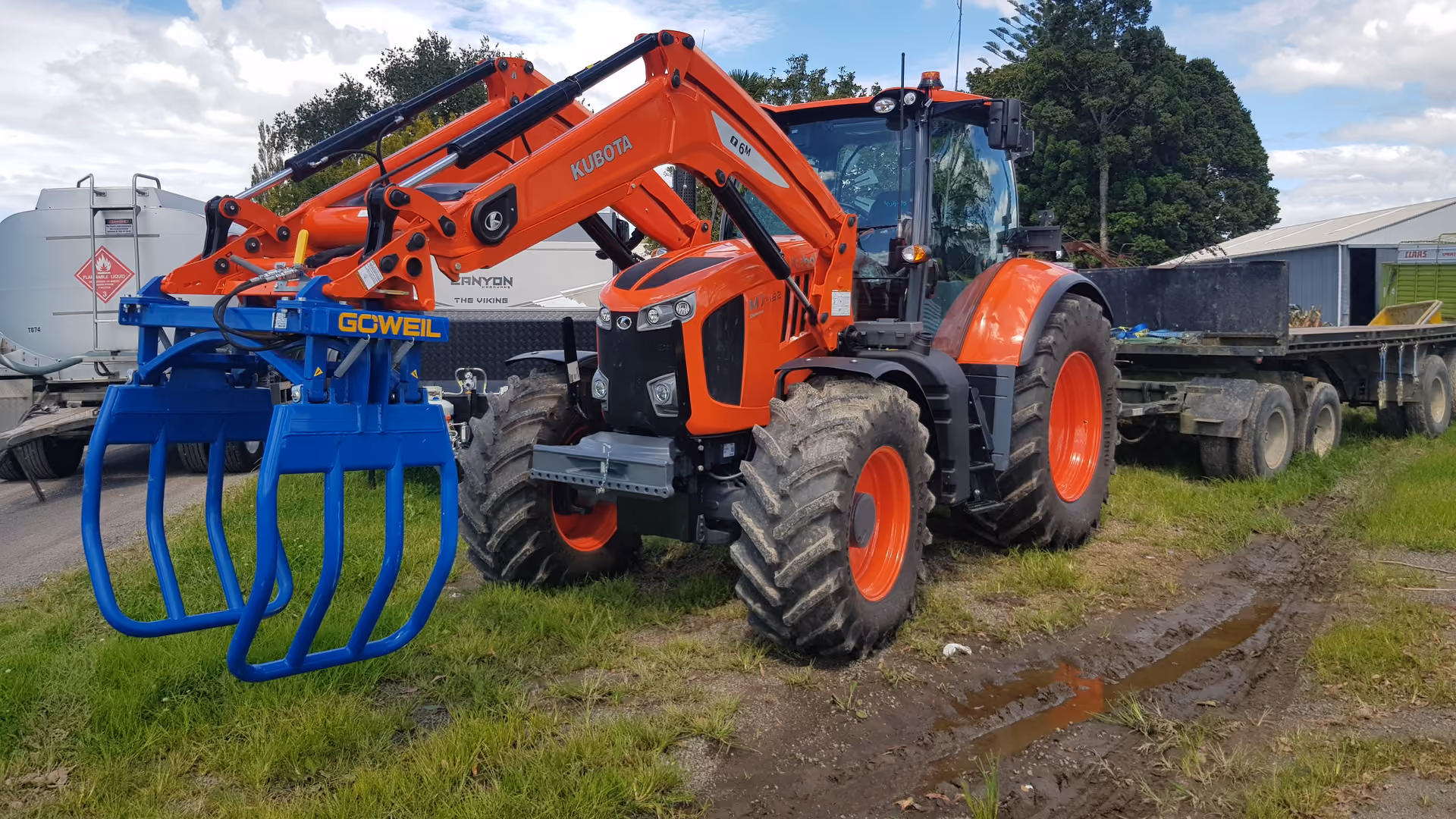 Kubota tractor fitted with a front grapple attachment in the yard