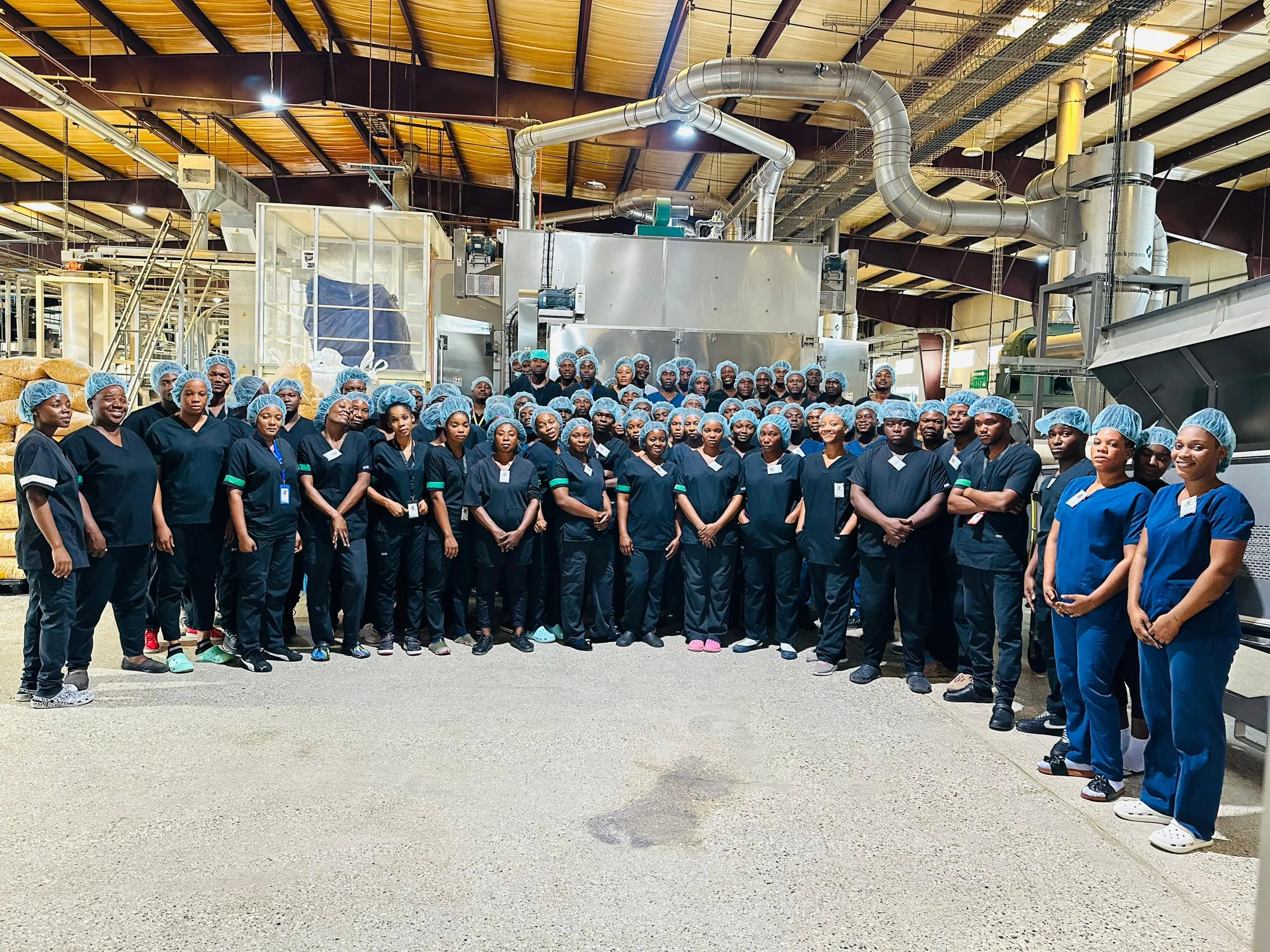 CFM factory workers in uniform and hairnets posing together on the production floor