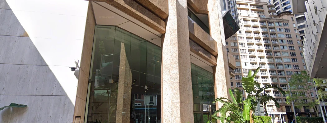 Modern building entrance with large glass windows and stone pillars surrounded by tall residential buildings.
