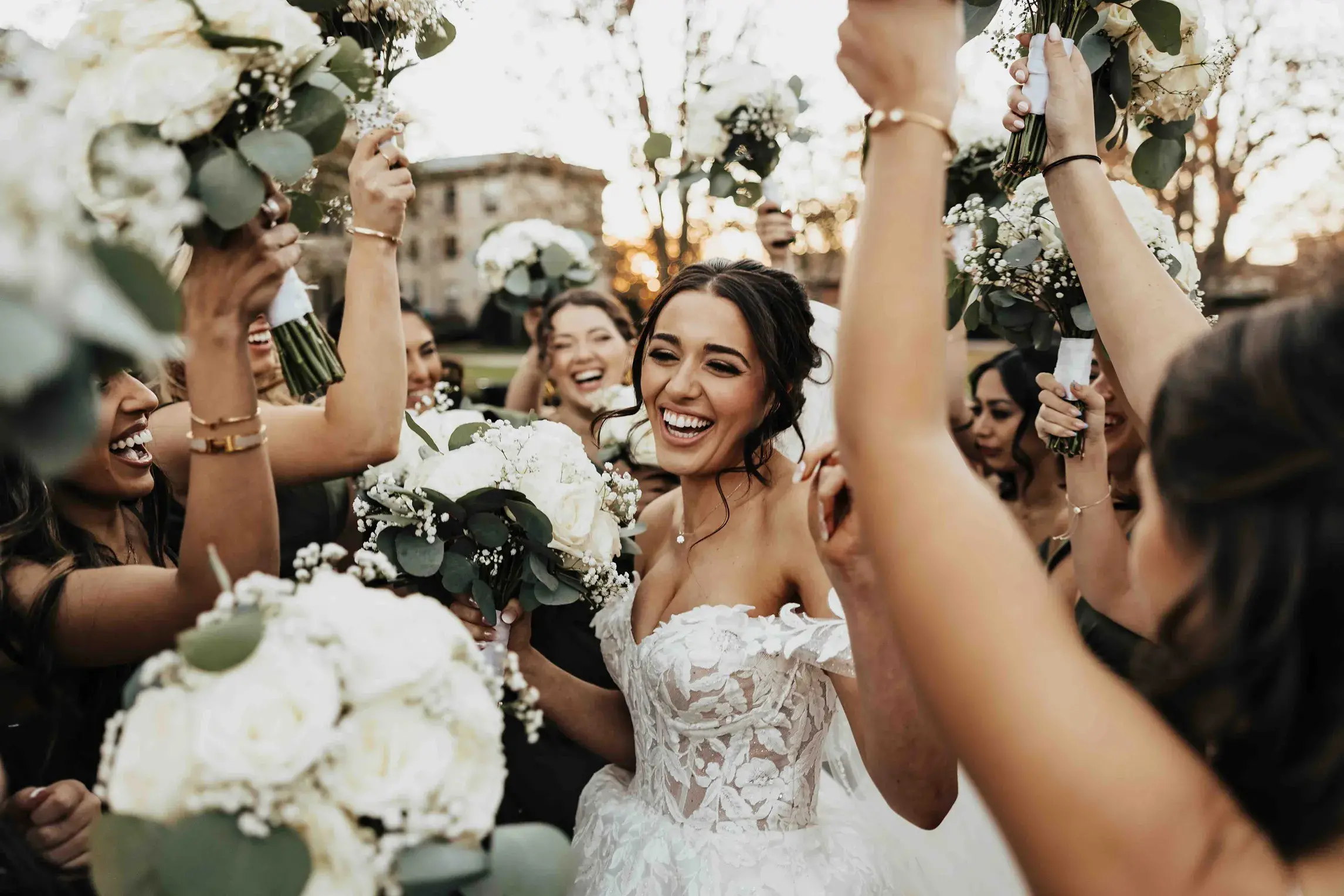 Bride smiling and celebrating with her bridesmaids, who raise their bouquets during a joyful wedding celebration in Providence, Rhode Island.