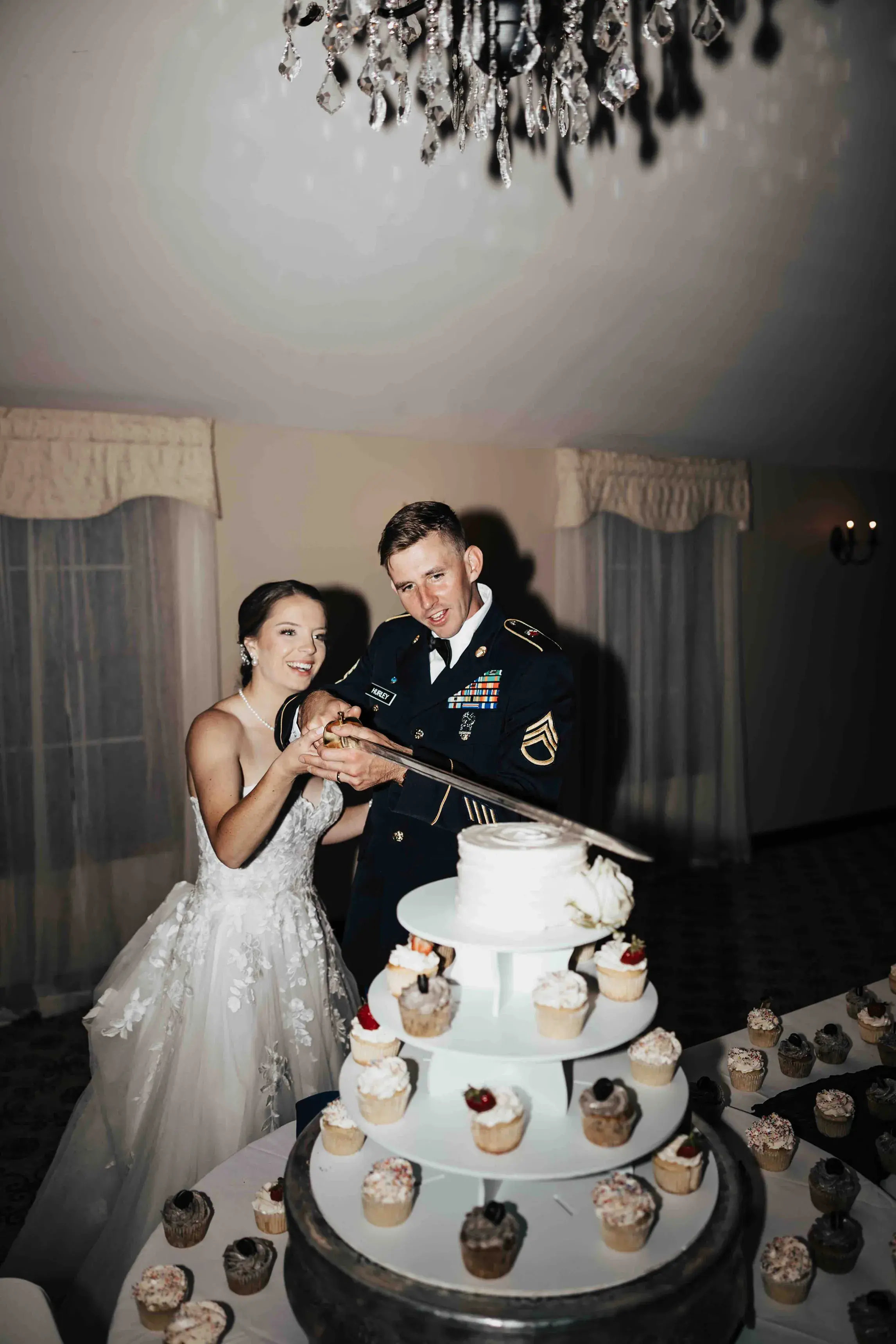 Bride and groom cutting their wedding cake with a ceremonial sword during their reception, celebrating with guests at a Western Massachusetts wedding in the Berkshires.