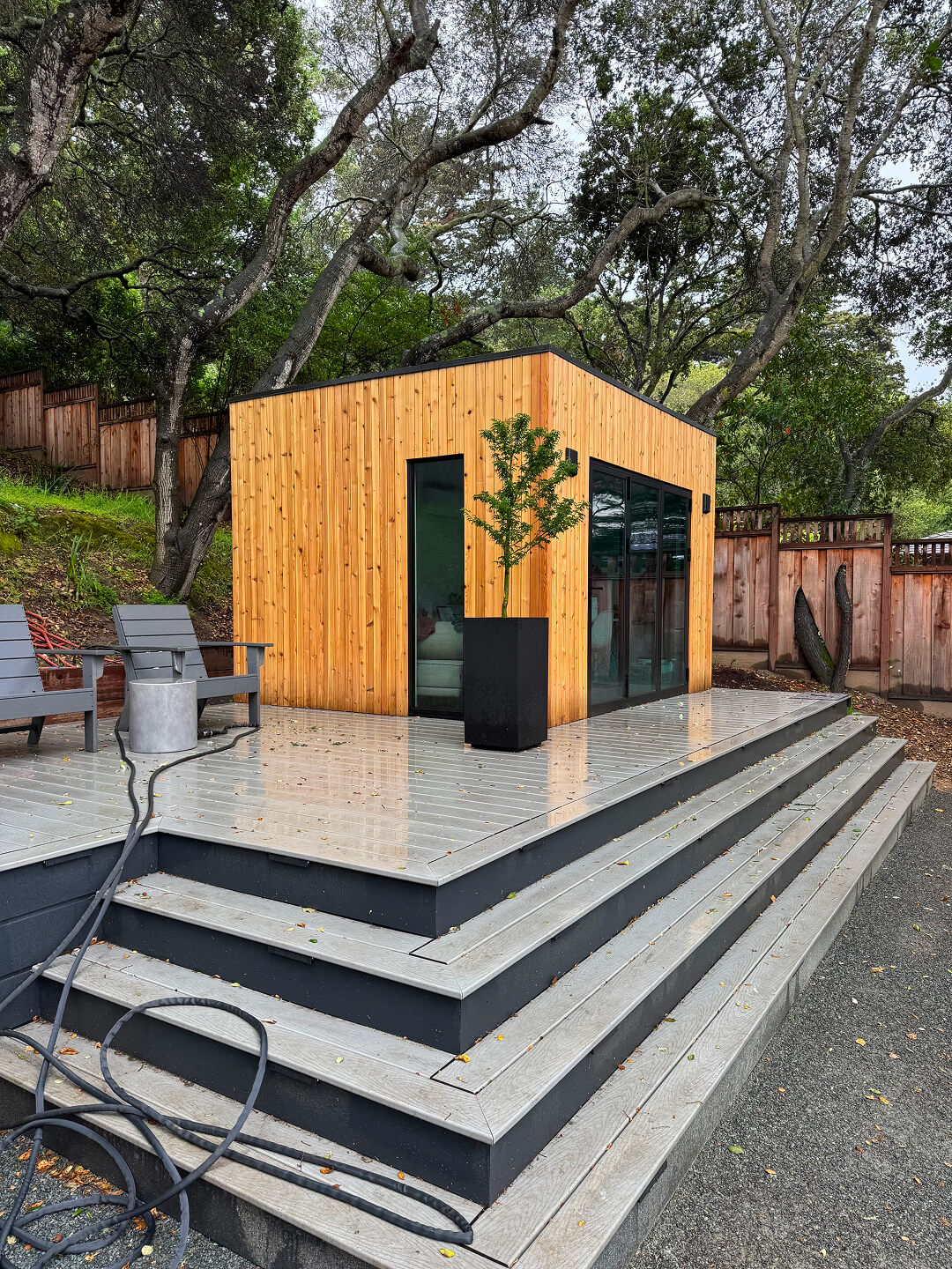 Modern Cube backyard studio shed with warm wood siding, large glass doors, and raised outdoor steps in the San Francisco Bay Area, California