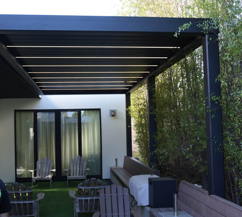 Modern covered patio with black pergola structure, outdoor seating, and built-in bench