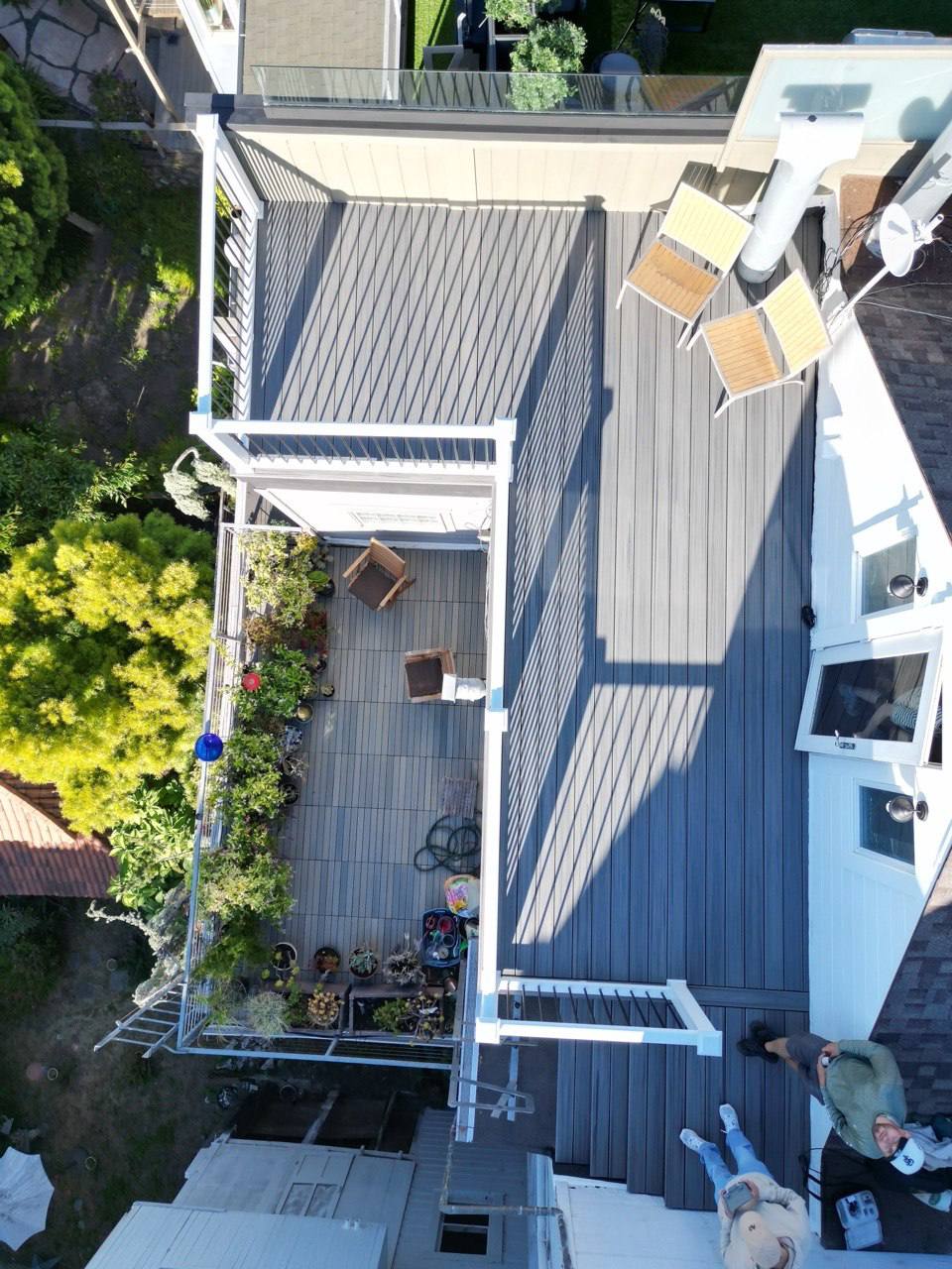 Aerial view of a modern white house with a gray composite deck and landscaped garden. Contemporary outdoor patio design