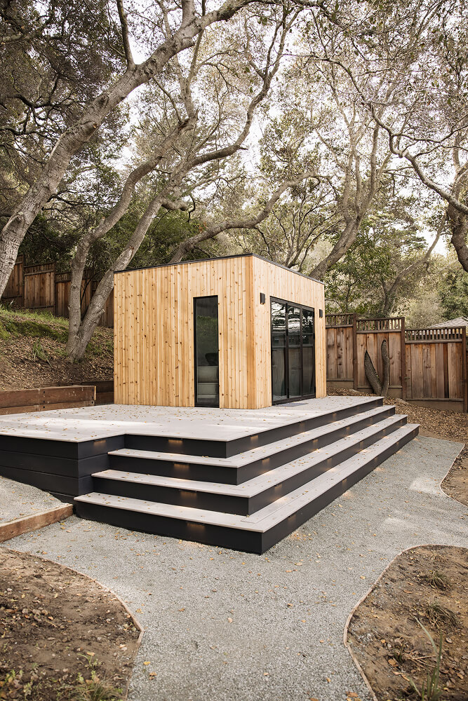 Modern Cube backyard studio shed with warm wood siding, large glass doors, and raised outdoor steps in the San Francisco Bay Area, California