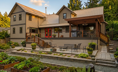 Modern dark house with wooden garage door and warm interior lights at dusk surrounded by rocks and trees.