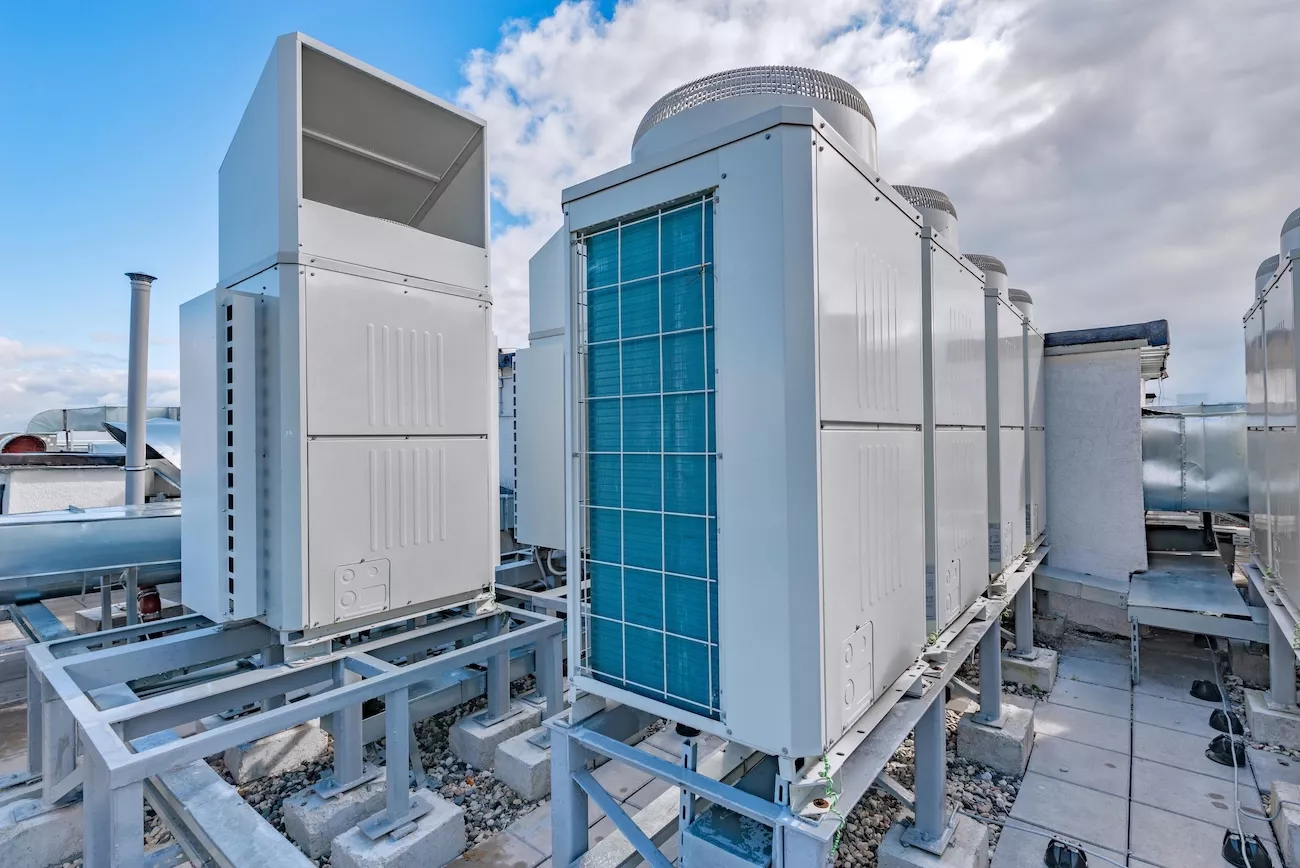 Commercial air conditioning installation with VRF outdoor condensing units mounted on steel frames on a business rooftop