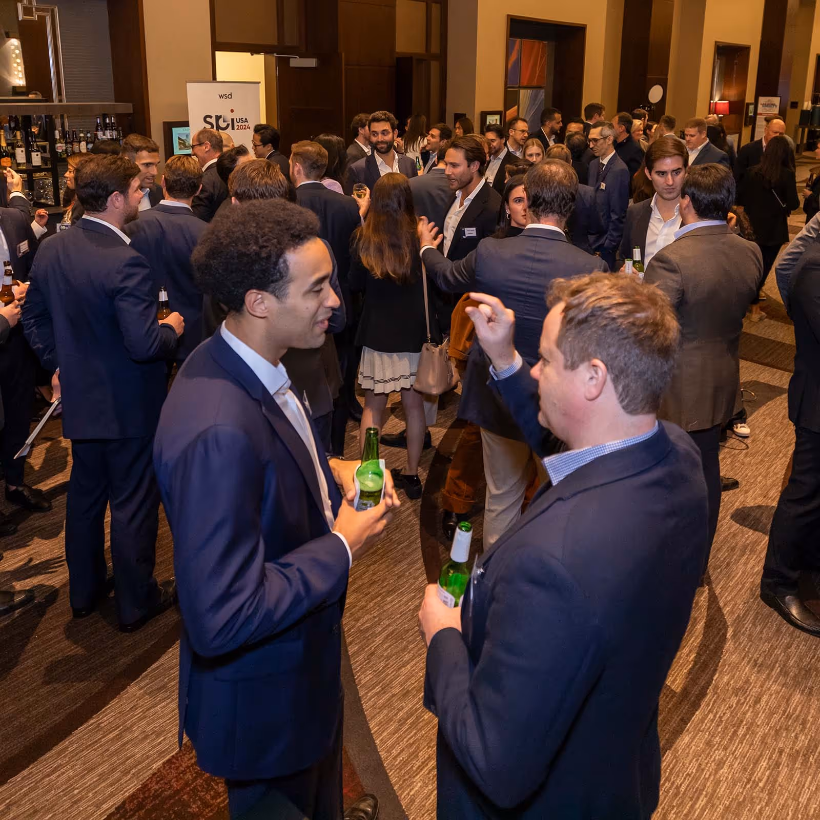 People dressed in business attire networking and holding drinks at SPI USA, the Structured Products Conference.