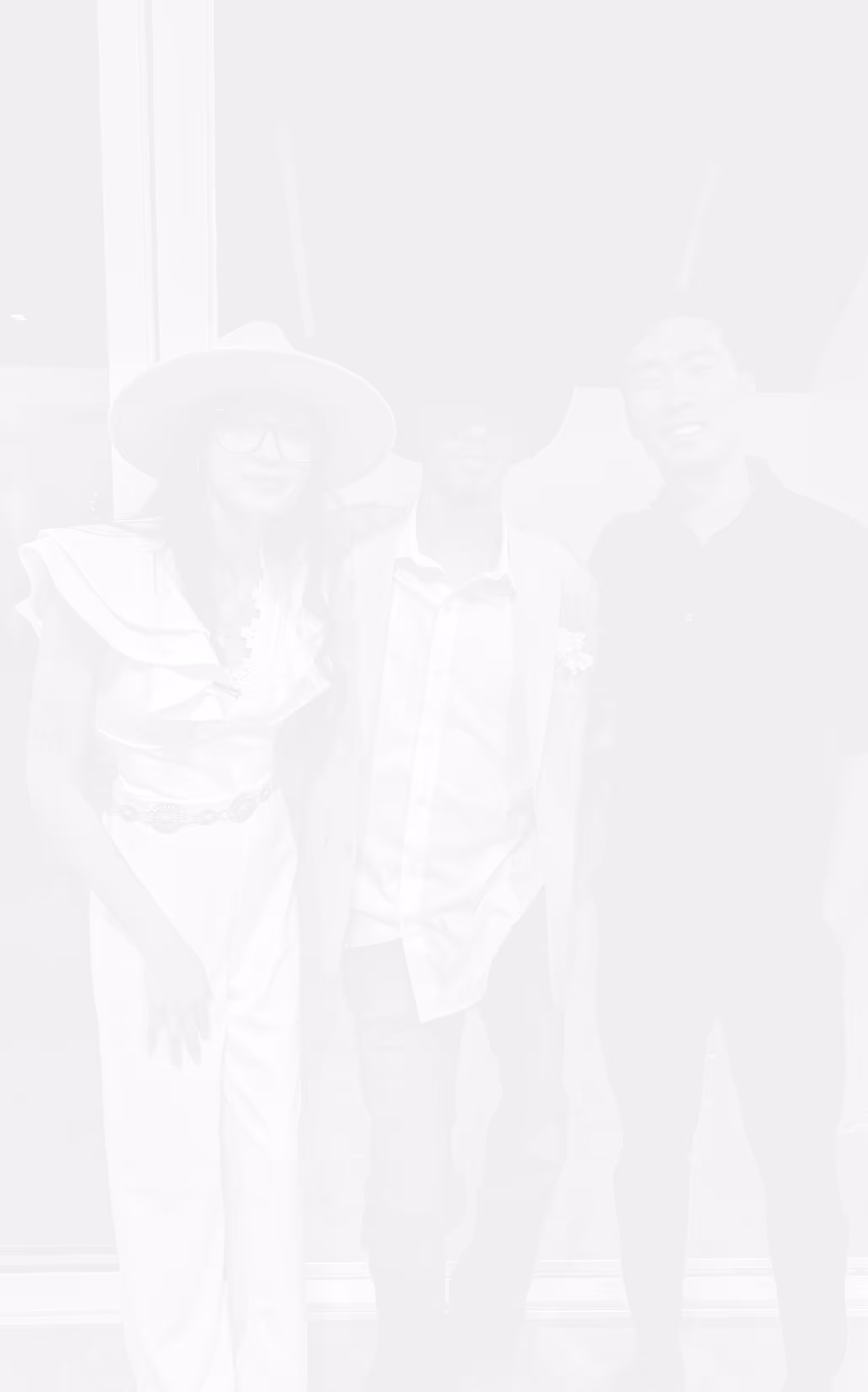 Three friends smiling, with one woman wearing a wide-brimmed hat and two men standing beside her.