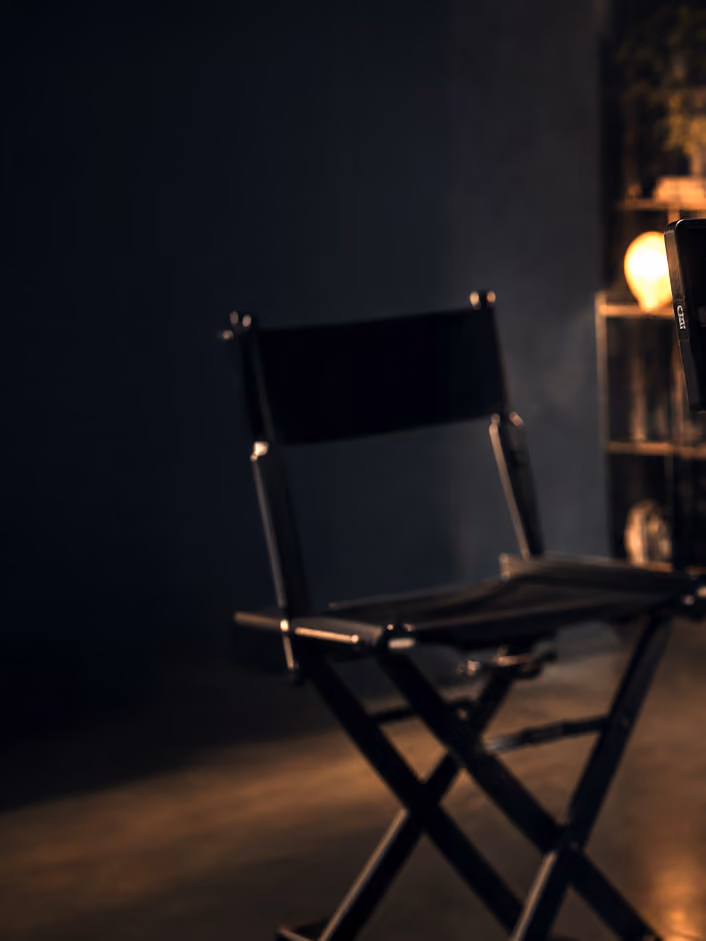 Director's chair on a moody, dimly lit film set.