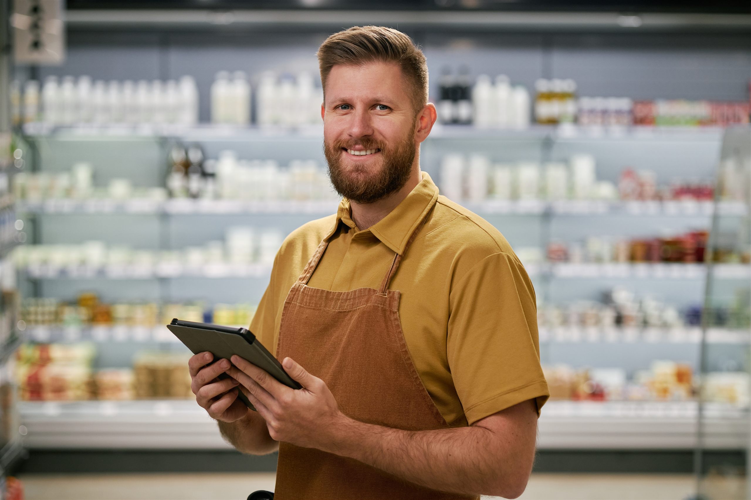 Glimlachende winkelondernemer met tablet in zijn supermarkt