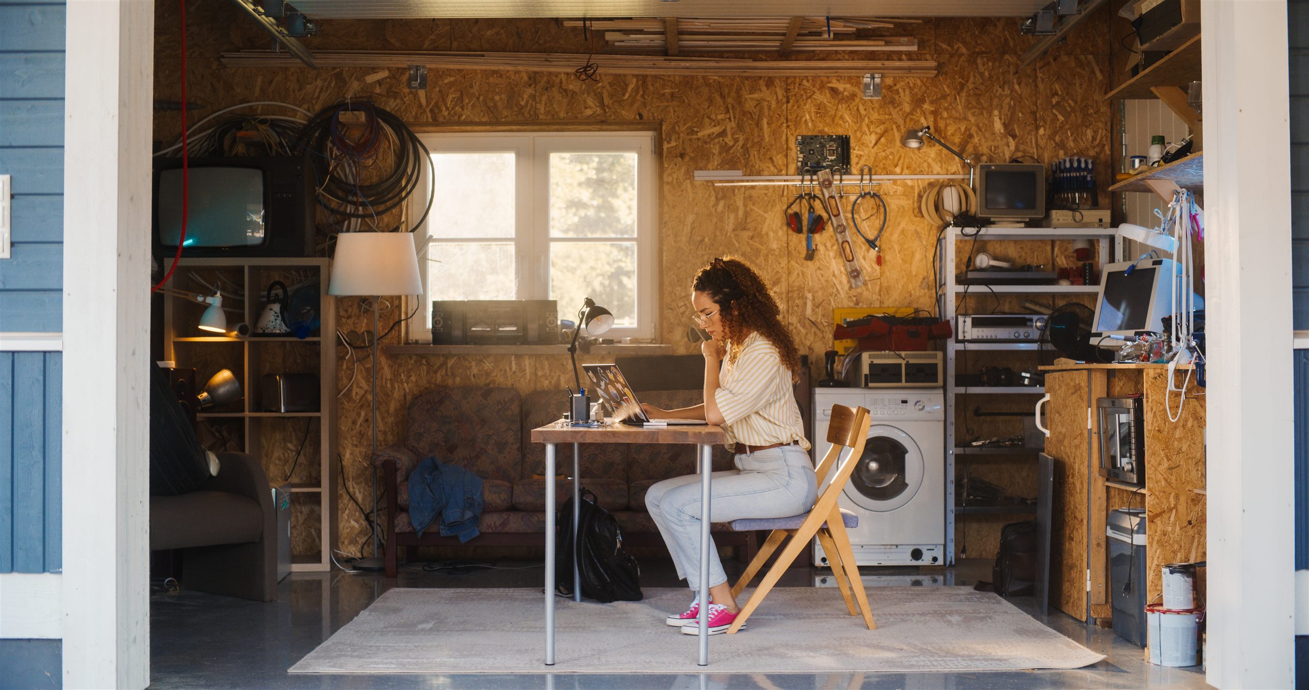 Onderneemster werkt geconcentreerd aan een bureau in haar overvolle garagewerkplaats